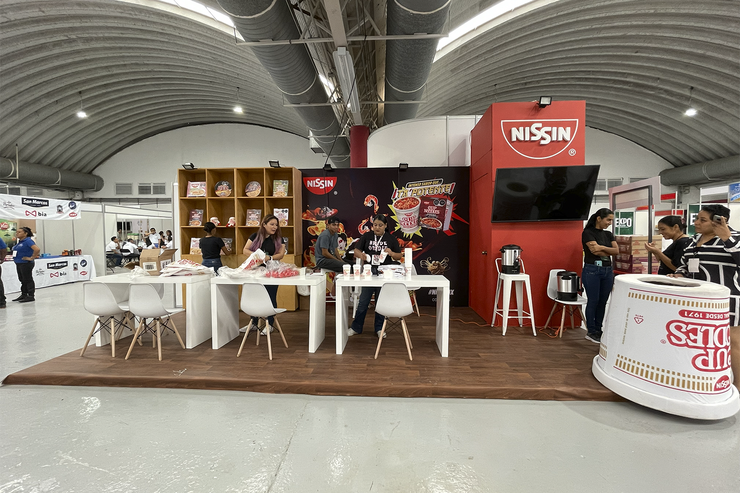 Expo Sánchez 2023: stand central con barra curva y mobiliario blanco