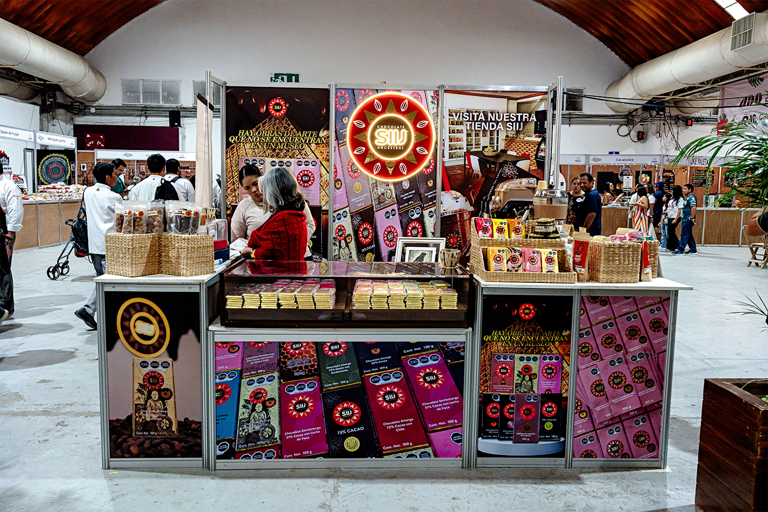 Stand tipo isla para chocolates SIU con gráficos vibrantes y logotipo iluminado.