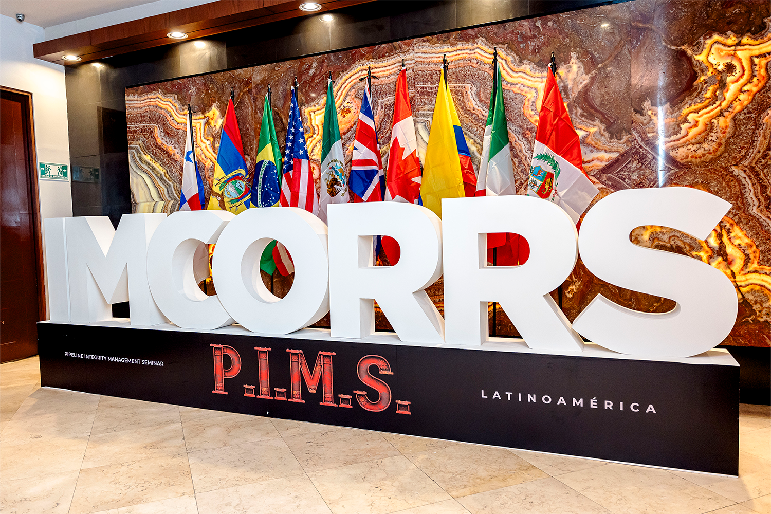 Letras 3D de IMCORRS y PIMS Latinoamérica con banderas internacionales, mostrando el alcance del evento.